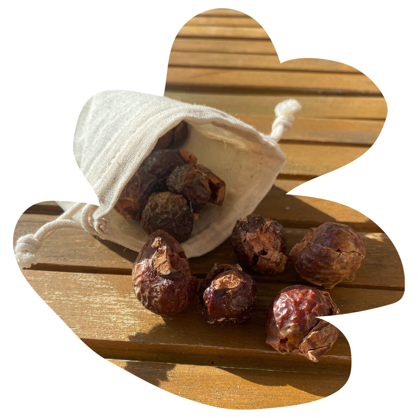 small cotton bag with soap nuts inside which are falling out of it onto a wooden table