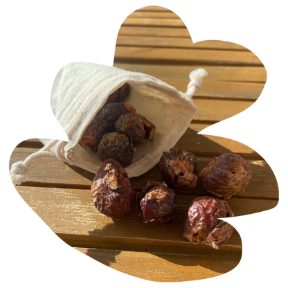 small cotton bag with soap nuts inside which are falling out of it onto a wooden table