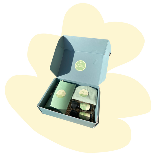 Image of a blue gift set with cream background in a squiggly shape. The gift set contains a blue box which says soap berries on the label, 2 essential oils with green labels and a lavender bag.